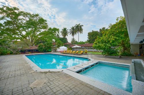 a swimming pool in a yard with chairs and trees at Casino Hotel - CGH Earth, Cochin in Cochin