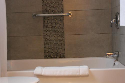 a bathroom with a tub and a toilet and a towel at Imperial Inn 1000 Islands in Gananoque