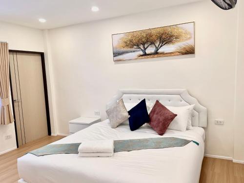 a bedroom with a white bed with pillows and a tree at Peace Homestay Hat Yai in Hat Yai