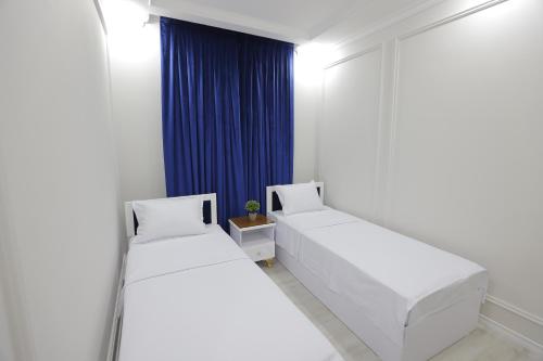 two beds in a room with a blue curtain at Beksaroy in Samarkand