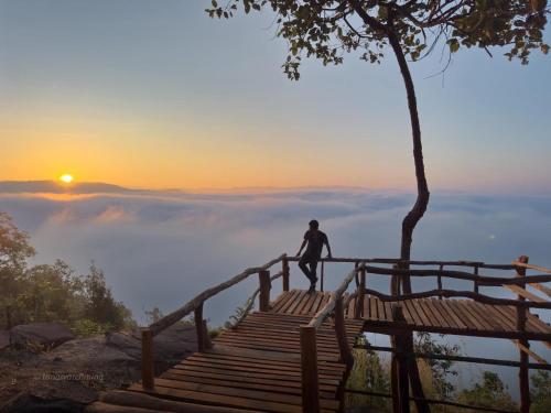 a man standing on a stairway with the sunset in the background at Pupiang po Da Arte Resort in Dan Sai