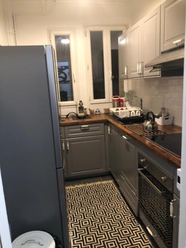 La cuisine est équipée d'un réfrigérateur, d'un évier et d'une cuisinière. dans l'établissement Bel appartement cosy et baroque, à Courbevoie