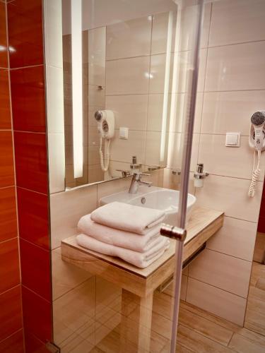 a bathroom with a sink and a mirror and towels at Hotel Arkadia Jelcz-Laskowice in Jelcz