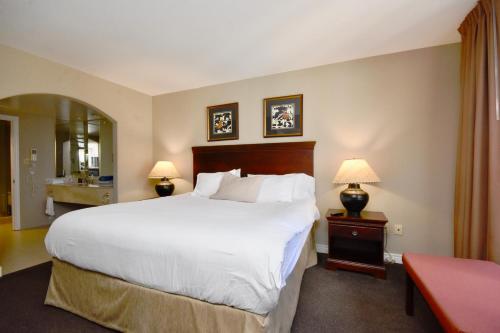 a bedroom with a large white bed and two lamps at Jacuzzi Suite with King bed, full kitchen in Shanty Bay