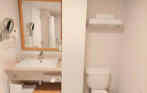 a bathroom with a sink and a toilet and a mirror at Holiday Inn Cuernavaca by IHG in Cuernavaca