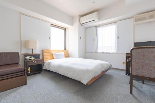 a bedroom with a bed and a chair and two windows at Hotel Alpha Inn Akita - Vacation STAY 67280v in Akita