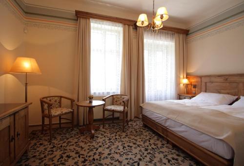 a bedroom with a bed and two chairs and a table at Pod lipami in Lázně Luhačovice