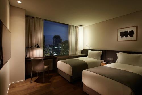 a hotel room with two beds and a desk and a window at Shilla Stay Guro - Guro Digital Complex Station in Seoul