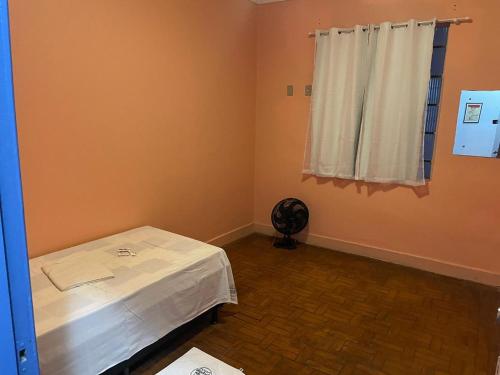 a room with a table and a window with a fan at Hotel Palace Econômico in Goiânia