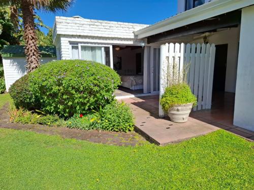 a house with a white fence and some bushes at Point Lodge Knysna in Knysna