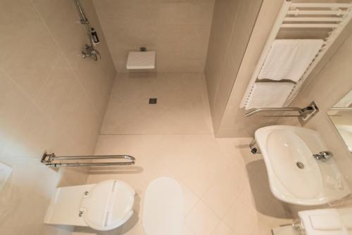 a white bathroom with a toilet and a sink at Horsky Hotel Sliezsky Dom in Vysoké Tatry