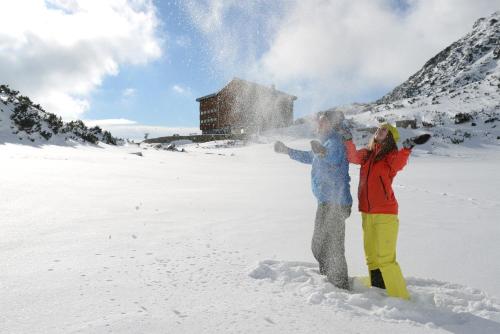two people are standing in the snow at Horsky Hotel Sliezsky Dom in Vysoké Tatry