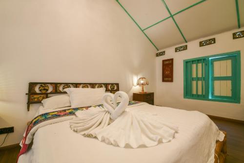 a bedroom with a white bed with a swan decoration at Ohana House-H3 in Melaka