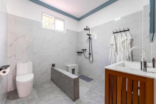 a bathroom with a toilet and a tub and a sink at Babylon Gardens Diani in Ukunda