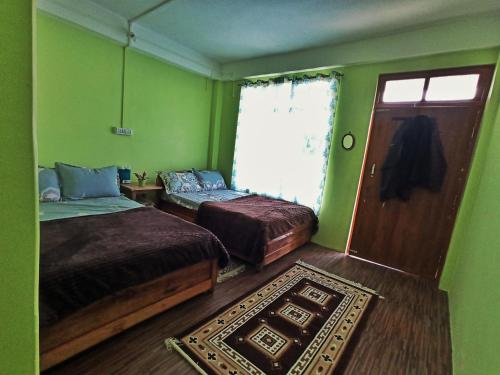 a green room with two beds and a door at Ratna Homestay & Restaurant in Darjeeling