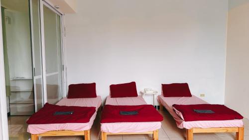 three beds in a room with red and pink sheets at 東海獨角獸 in Longjing