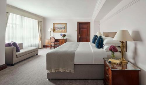 a hotel room with a large bed and a couch at Hyatt Regency London - The Churchill in London