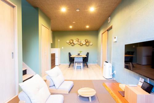 a living room with a table and white chairs at 貸し切り宿 世紡 YOTSUMUGI sakazuki and iyasaka in Yufuin