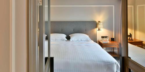 a bedroom with a large bed with white sheets at Hyatt Regency London - The Churchill in London