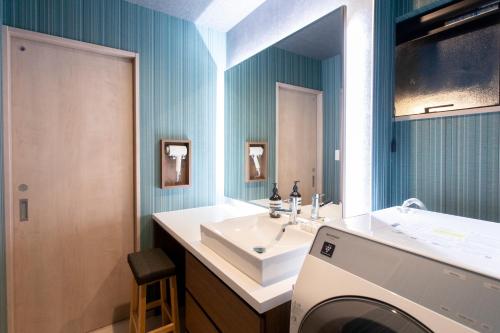 a bathroom with a sink and a washing machine at 貸し切り宿 世紡 YOTSUMUGI sakazuki and iyasaka in Yufuin