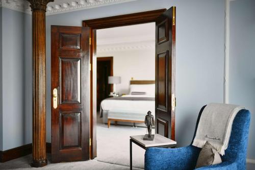 a bedroom with a bed and a blue chair at Hyatt Regency London - The Churchill in London