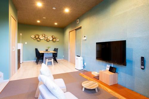 a living room with a couch and a tv at 貸し切り宿 世紡 YOTSUMUGI sakazuki and iyasaka in Yufuin