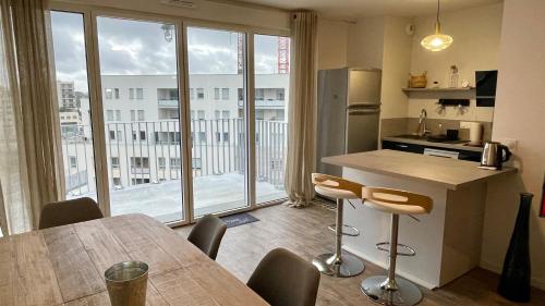 une cuisine avec une table et des chaises ainsi qu'une grande fenêtre dans l'établissement Au Bord'eaux de Malou, à Bordeaux