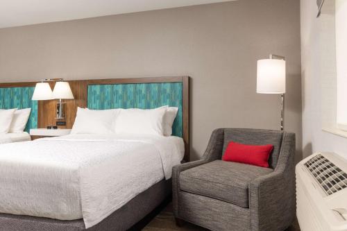 a bedroom with a bed and a chair with a red pillow at Hampton Inn Kalispell in Kalispell