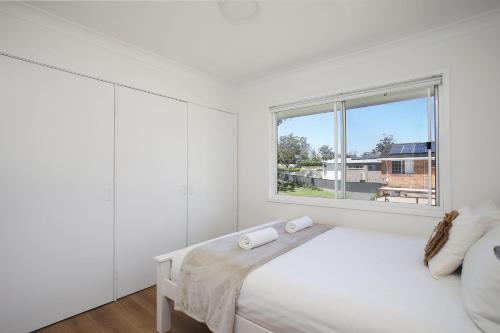 a white bedroom with a bed and a window at Sanctuary Bliss in Sanctuary Point
