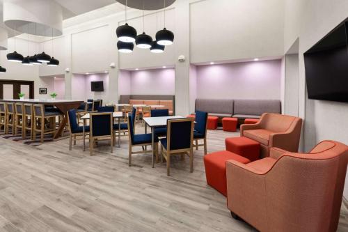 a waiting room with tables and chairs and a cafeteria at Hampton Inn & Suites Saginaw in Saginaw