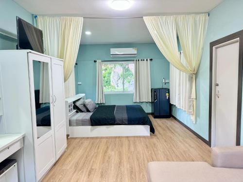 a bedroom with blue walls and a bed and a window at นพรัตน์การ์เด้นฮิลล์ in Uthai Thani
