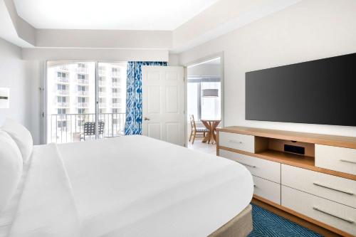 a white bedroom with a large bed and a flat screen tv at Hilton Vacation Club The Cove on Ormond Beach in Ormond Beach