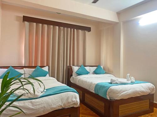 two beds in a room with blue pillows at Hotel Resunga Arjun in Kathmandu