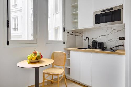 - une cuisine avec une table et un bol de fruits dans l'établissement Bluestay 293 - Studio Cozy à Paris 17, à Paris