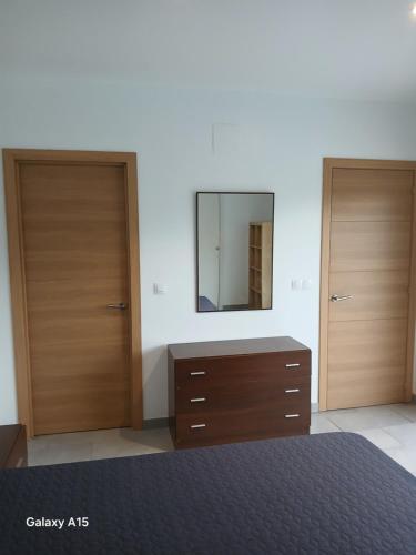 a bedroom with two doors and a dresser with a mirror at Appartement Almadrava Roses in Roses