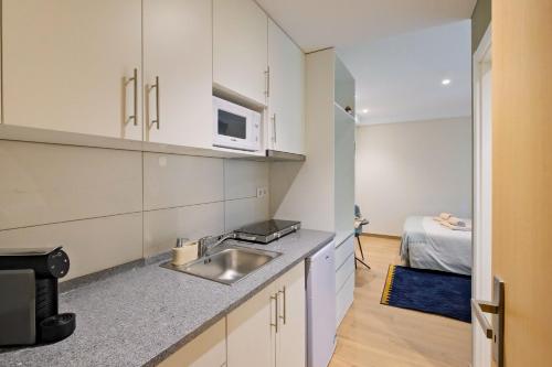 a kitchen with a sink and a microwave at Lovely studio fully equipped near subway N7 in Lisbon