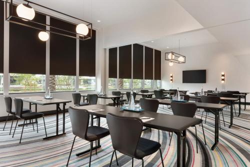 a dining room with tables and chairs and a screen at The Viv Hotel, Anaheim, a Tribute Portfolio Hotel in Anaheim
