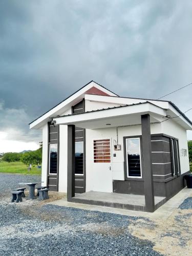 a small white house with a bench in front of it at Dmana Homestay Arau Perlis Tiny House in Arau