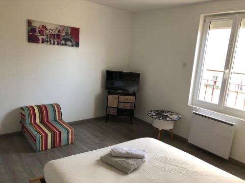 une chambre avec un lit, une télévision et une chaise dans l'établissement Grande chambre côté jardin, à Château-du-Loir