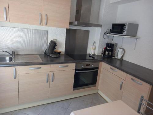 La cuisine est équipée de placards en bois, d'un évier et d'un four micro-ondes. dans l'établissement Maison à 50 m de la plage, à Banyuls-sur-Mer