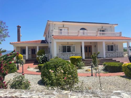 a large white house with bushes and flowers at Letymvou Terrace in Letimbou