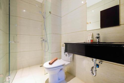 a bathroom with a toilet and a glass shower at Minimalist Style Studio Brooklyn Alam Sutera Apartment near IKEA By Travelio in Dongkal Dua