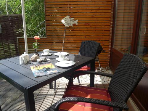 a black table and chairs on a patio at Ferienhaus an der Buche "Gartenblick" in Neue Tiefe Fehmarn