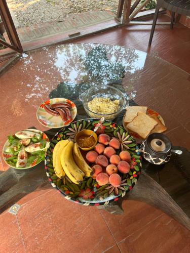 Una mesa cubierta con un plato de fruta y pan. en Minivets Nest, en Rāmnagar