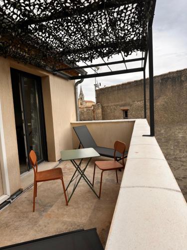 - une terrasse avec 2 chaises et une table dans un bâtiment dans l'établissement Le Cœur du Village, à Sainte-Cécile-les-Vignes