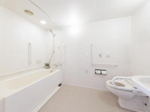 a white bathroom with a toilet and a sink at ART HOTEL Kashima Central in Kamisu