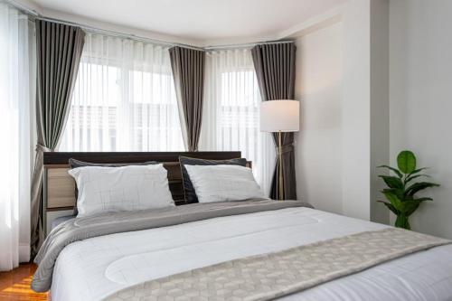 a bedroom with a large white bed with windows at Private Pool Villa Resort style, Heart in bkk ,metro,cabaret show,RCA, jodd fair,chatuchak in Bangkok