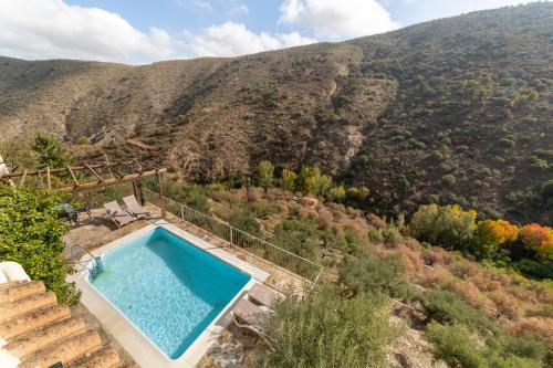 an outdoor swimming pool with a mountain in the background at La Casa Al Revés in Laroya
