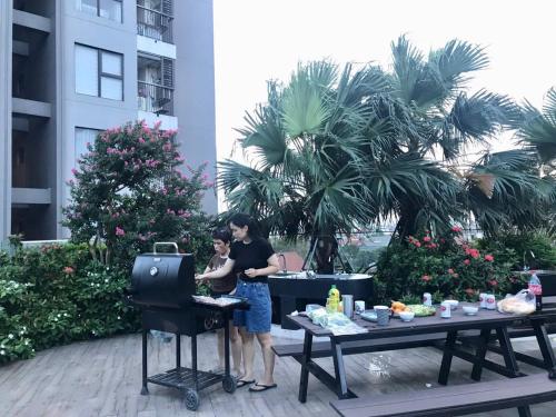 two people standing at a table with a grill at Củi Homestay Oasis Ecopark in Kim Quan
