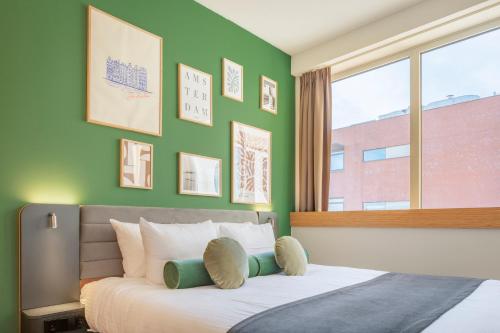 a bedroom with a bed with a green wall at Maxhotel Amsterdam Airport Schiphol in Hoofddorp